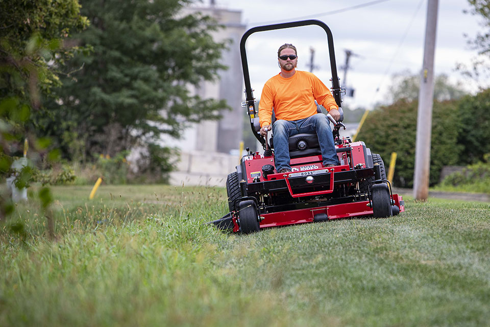 Guy mowing on a Country Clipper Boss XL commercial grade zero-turn mower with joystick steering.