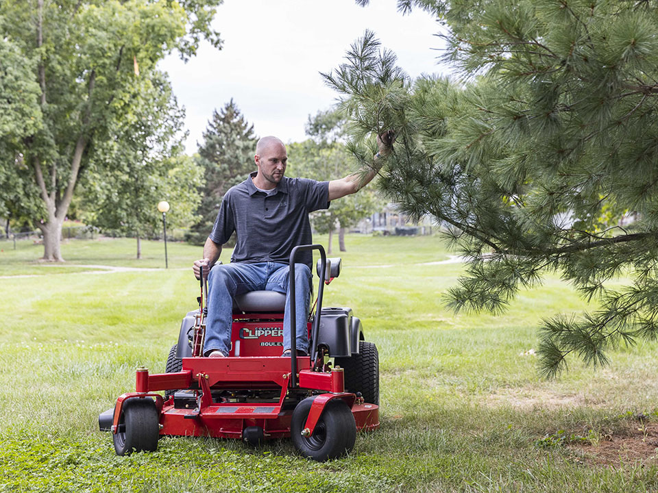 Guy mowing the lawn on a Country Clipper Boulevard residential grade zero-turn mower with joystick steering.