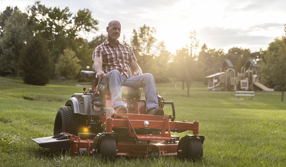 Guy mowing grass on a Country Clipper XLT residential grade zero-turn mower with joystick steering.